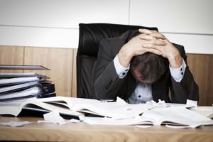 man overloaded with work causing a stressful work environment
